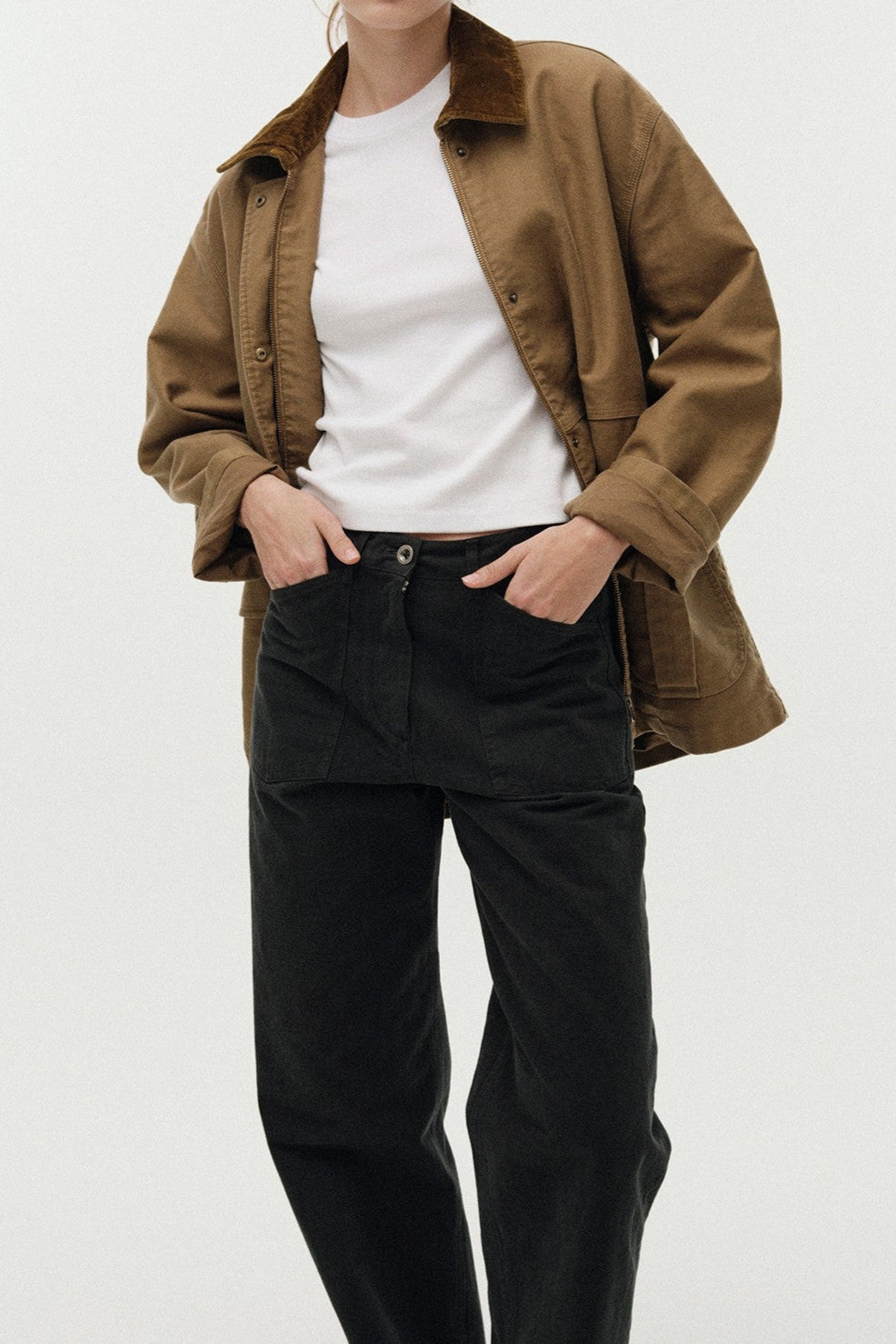 Person wearing a brown jacket, white shirt, and black pants on a white background